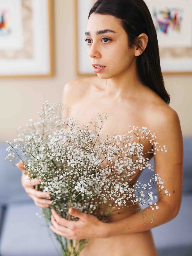 Ericka Benítez de pie en un interior, con una brazada de paniculata sobre el pecho.