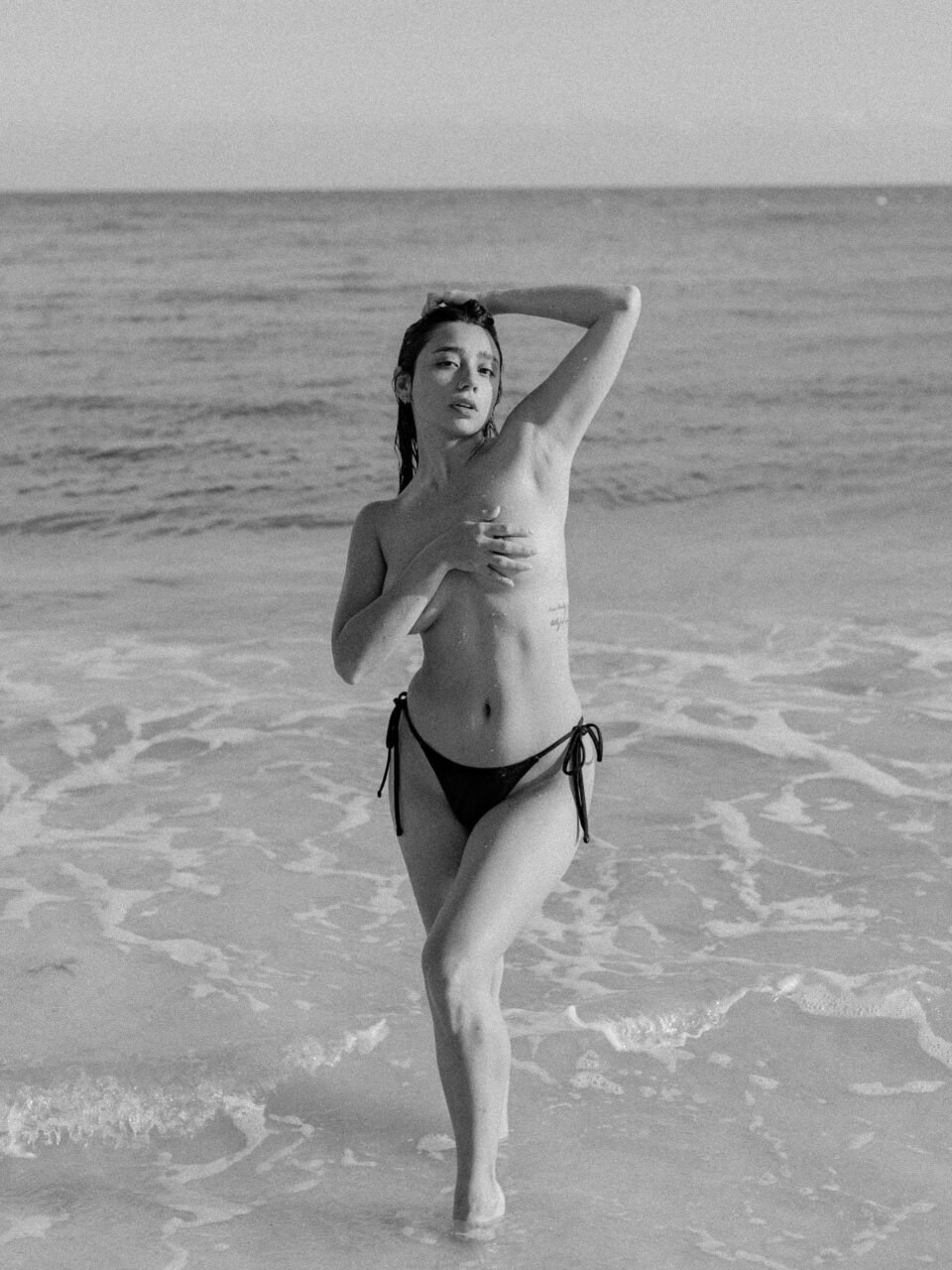Fotografía en blanco y negro de Ericka Benítez en la orilla del mar.