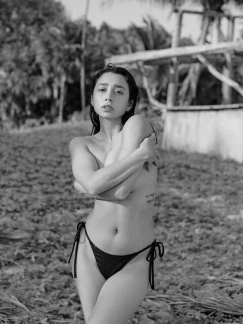 Retrato en blanco y negro de Ericka Benítez entre la vegetación de la playa.