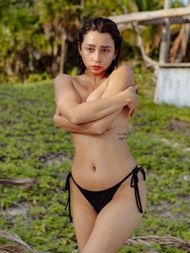 Ericka Benítez de pie en la playa al final de la tarde, con los brazos cruzados sobre el pecho.